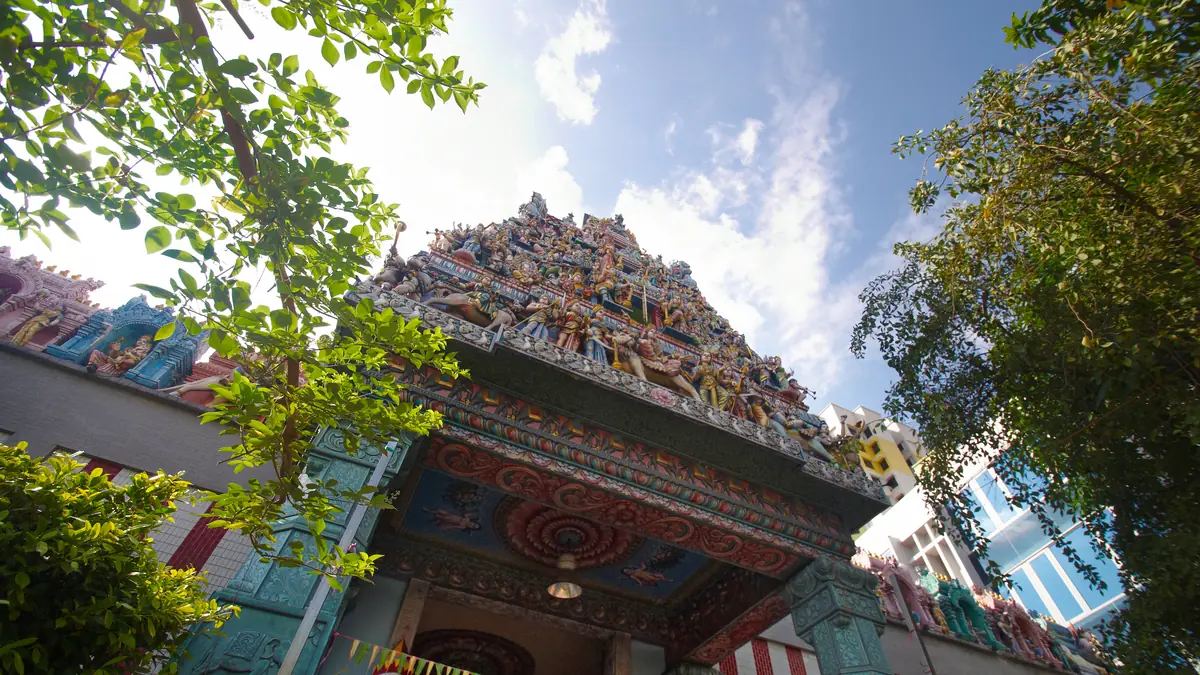 Little India — The ornately carved gopuram tower of Sri Veeramakaliamman Temple in Little India, framed by trees against a blue sky