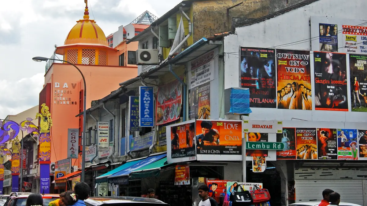 Little India — A busy Little India street of shopfronts and film posters with a Hindu temple dome rising above the rooftops