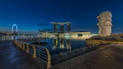 Merlion Park — The Merlion statue spouting water at dusk, with Marina Bay Sands and the Singapore Flyer across the bay